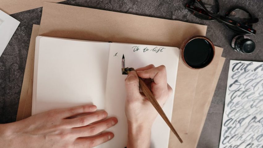 Top view of a to-do list with calligraphy pen on a desk with ink.